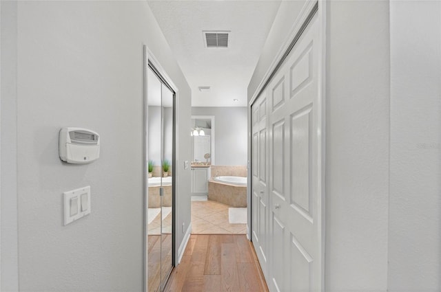 11716 Strandhill Ct, Lakewood Ranch, FL 34202 - hall featuring visible vents, light wood-style flooring, and a textured ceiling