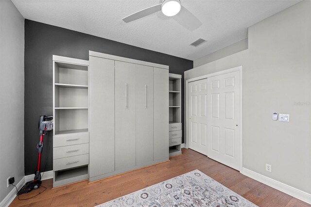 11716 Strandhill Ct, Lakewood Ranch, FL 34202 - bedroom featuring a textured ceiling, visible vents, baseboards, wood finished floors, and a ceiling fan