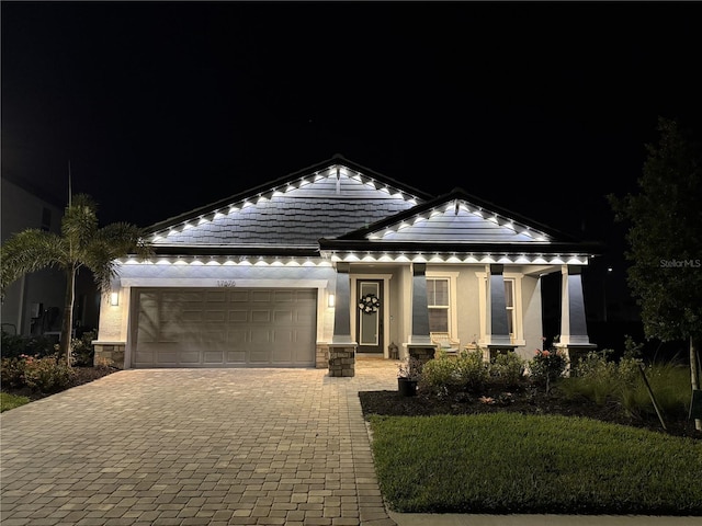 view of front facade with a tiled roof, a garage, stucco siding, and decorative driveway
