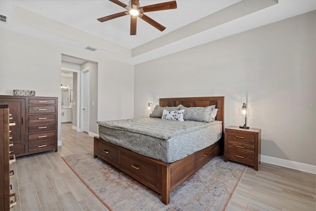 bedroom featuring visible vents, baseboards, a raised ceiling, and light wood-style floors
