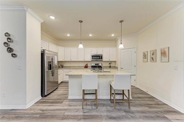 10015 Marbella Dr, Bradenton, FL 34211 - kitchen with appliances with stainless steel finishes, white cabinetry, ornamental molding, light wood-type flooring, and an island with sink