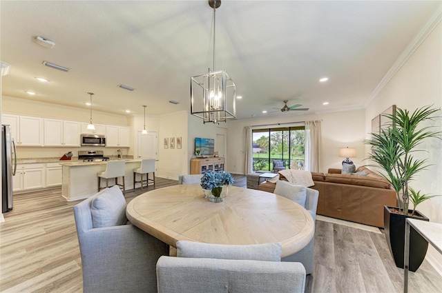 10015 Marbella Dr, Bradenton, FL 34211 - dining area featuring light wood-style floors, ceiling fan, crown molding, recessed lighting, and a chandelier