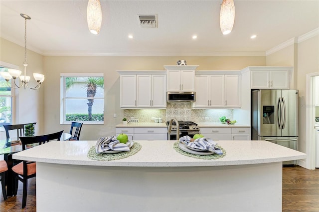 7278 Lismore Ct, Lakewood Ranch, FL 34202 - kitchen featuring appliances with stainless steel finishes, white cabinets, a chandelier, a center island with sink, and backsplash