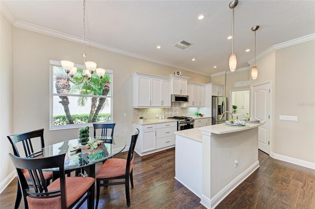 7278 Lismore Ct, Lakewood Ranch, FL 34202 - kitchen featuring appliances with stainless steel finishes, an island with sink, light countertops, white cabinetry, and crown molding