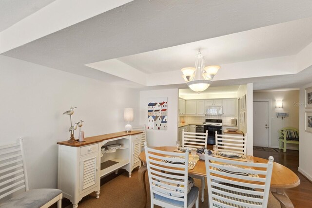 5055 Gulf Of Mexico Dr Unit 422, Longboat Key, FL 34228 - dining space featuring a tray ceiling and an inviting chandelier