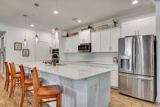 2707 162nd Ave E, Parrish, FL 34219 - kitchen with stainless steel appliances, ornamental molding, white cabinets, tasteful backsplash, and light wood finished floors