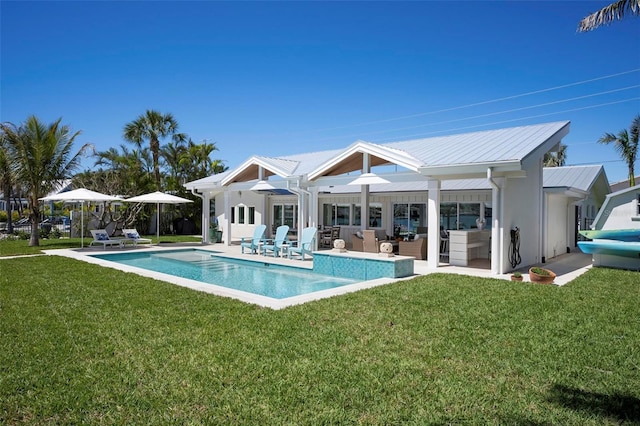 527 Key Royale Dr, Holmes Beach, FL 34217 - back of property featuring stucco siding, a lawn, a patio area, metal roof, and an outdoor pool
