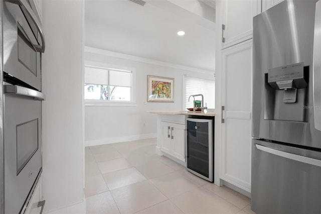 527 Key Royale Dr, Holmes Beach, FL 34217 - kitchen with ornamental molding, white cabinets, stainless steel refrigerator with ice dispenser, wine cooler, and a sink
