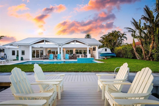527 Key Royale Dr, Holmes Beach, FL 34217 - back of property at dusk featuring a wooden deck and a lawn
