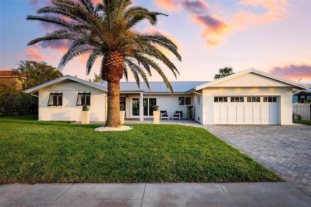 527 Key Royale Dr, Holmes Beach, FL 34217 - ranch-style home featuring a yard, an attached garage, metal roof, stucco siding, and decorative driveway