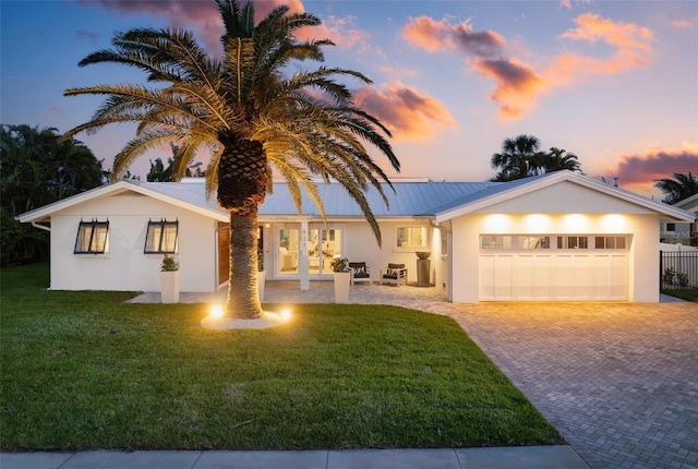 527 Key Royale Dr, Holmes Beach, FL 34217 - single story home featuring stucco siding, a lawn, metal roof, an attached garage, and driveway