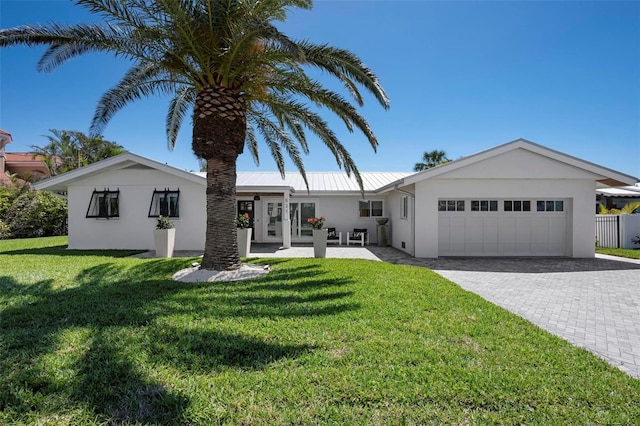 527 Key Royale Dr, Holmes Beach, FL 34217 - single story home with stucco siding, decorative driveway, an attached garage, a front yard, and metal roof