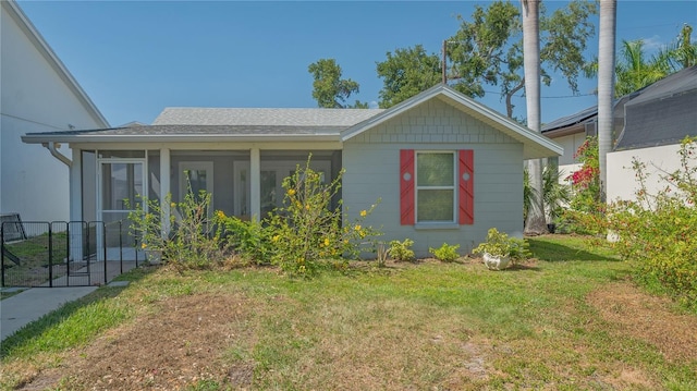 view of home's exterior with a yard, a sunroom, and a shingled roof
