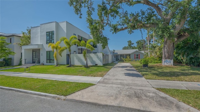 view of front of property featuring driveway, stucco siding, a front yard, and fence