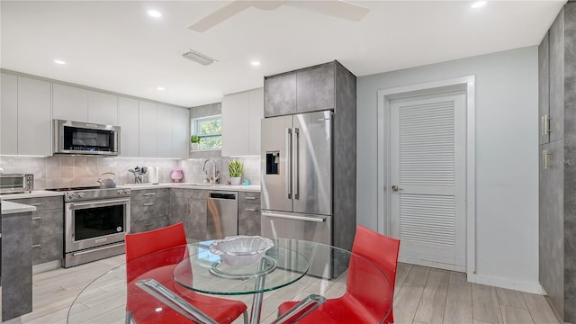 kitchen featuring light wood finished floors, a sink, a toaster, appliances with stainless steel finishes, and decorative backsplash