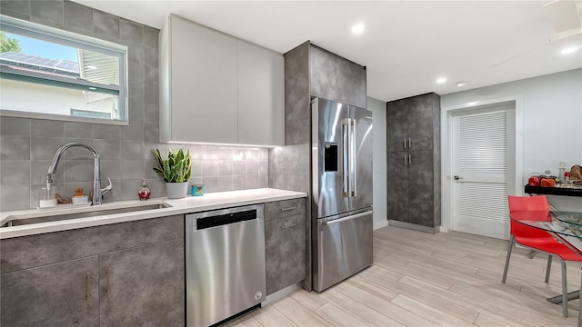 kitchen featuring stainless steel appliances, modern cabinets, a sink, light wood-style floors, and light countertops