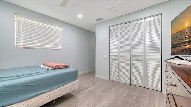 bedroom with a closet, baseboards, ceiling fan, visible vents, and light wood-style floors