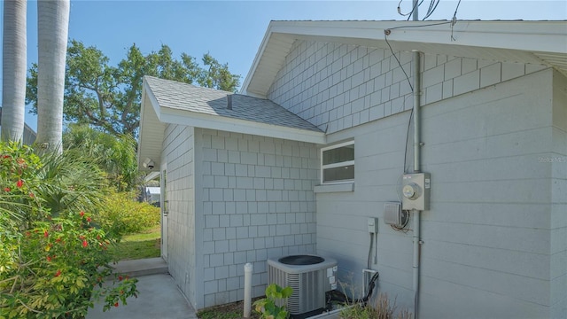 view of home's exterior with a shingled roof and cooling unit