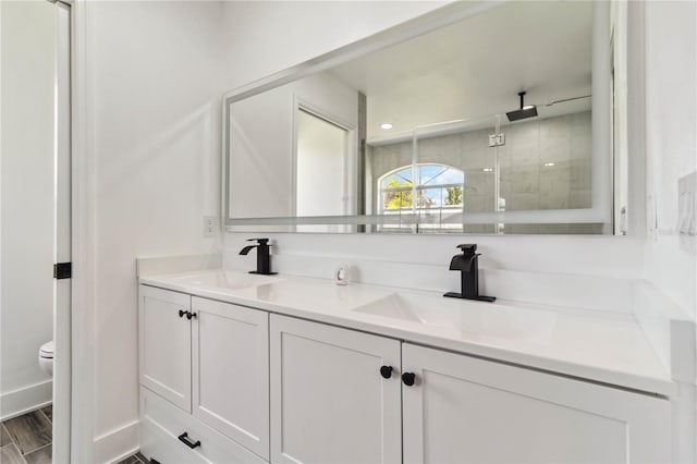 full bathroom featuring double vanity, a sink, toilet, and a shower stall