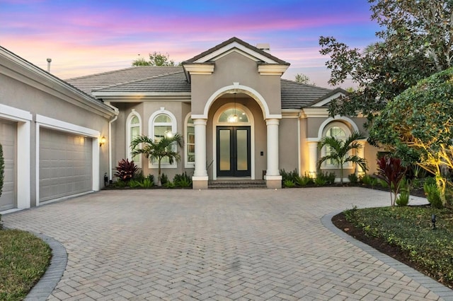 7257 Greystone St, Lakewood Ranch, FL 34202 - view of front of home with french doors, stucco siding, an attached garage, a tiled roof, and decorative driveway