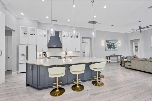 7257 Greystone St, Lakewood Ranch, FL 34202 - kitchen featuring white cabinetry, premium range hood, high end fridge, decorative backsplash, and a large island