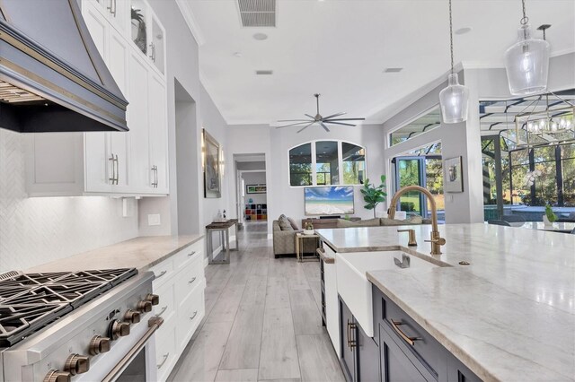 7257 Greystone St, Lakewood Ranch, FL 34202 - kitchen featuring light stone counters, a sink, open floor plan, range, and under cabinet range hood