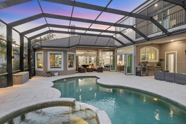 7257 Greystone St, Lakewood Ranch, FL 34202 - pool at dusk featuring an outdoor hangout area, a lanai, a patio, exterior kitchen, and a pool with connected hot tub