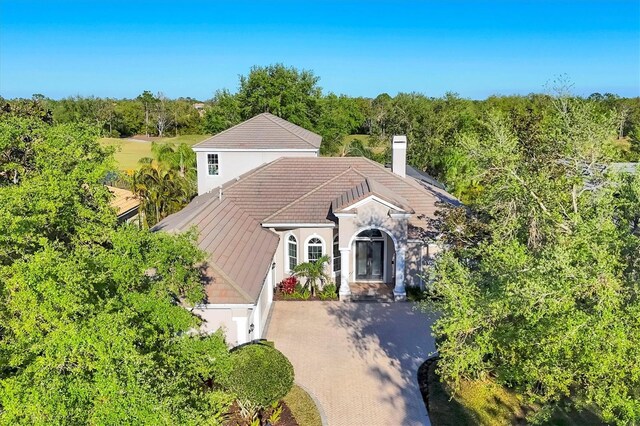 7257 Greystone St, Lakewood Ranch, FL 34202 - view of front facade featuring stone siding, a chimney, stucco siding, a tiled roof, and decorative driveway