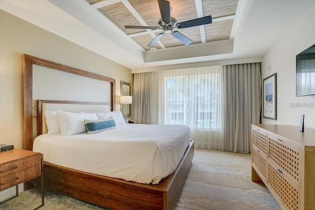 bedroom with a tray ceiling, light carpet, and a ceiling fan