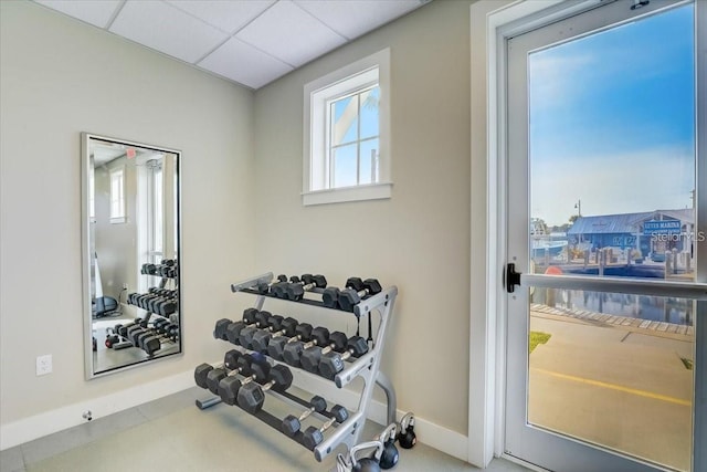 workout area featuring baseboards and a paneled ceiling