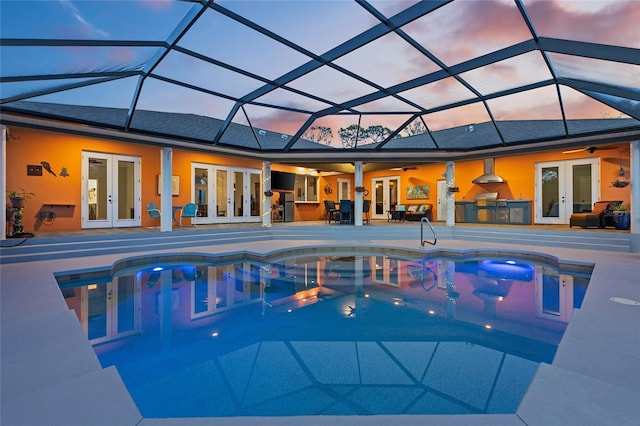 outdoor pool with an outdoor kitchen, a ceiling fan, glass enclosure, french doors, and a patio