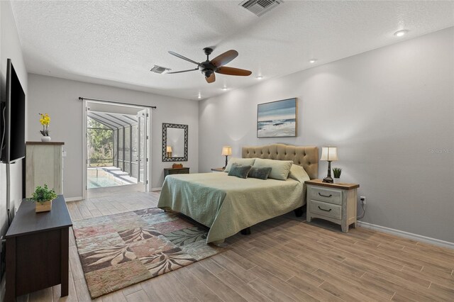 bedroom with wood finished floors, visible vents, and access to exterior
