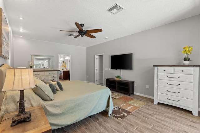 bedroom featuring visible vents, light wood-style floors, baseboards, ceiling fan, and ensuite bathroom