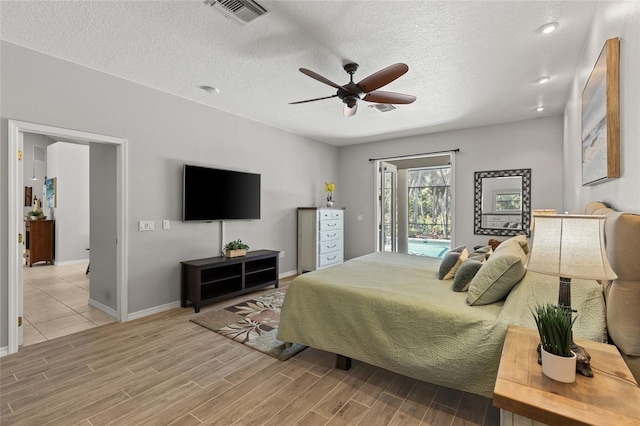 bedroom with wood finished floors, visible vents, access to exterior, baseboards, and a textured ceiling