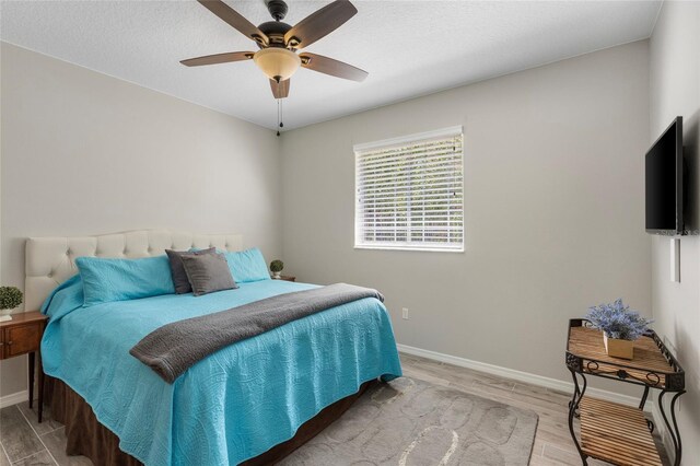 bedroom with ceiling fan, baseboards, and light wood-style floors
