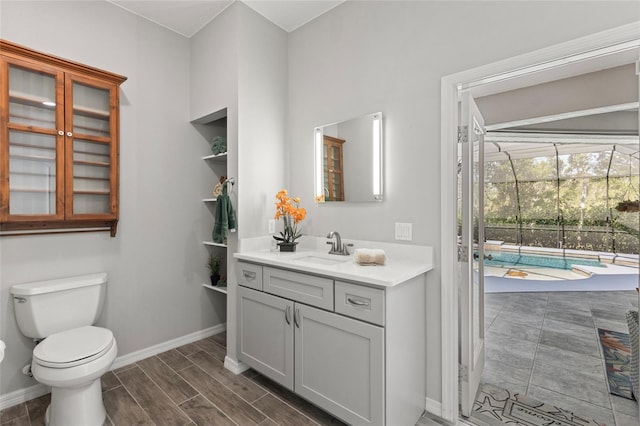 bathroom featuring baseboards, wood finished floors, vanity, and toilet