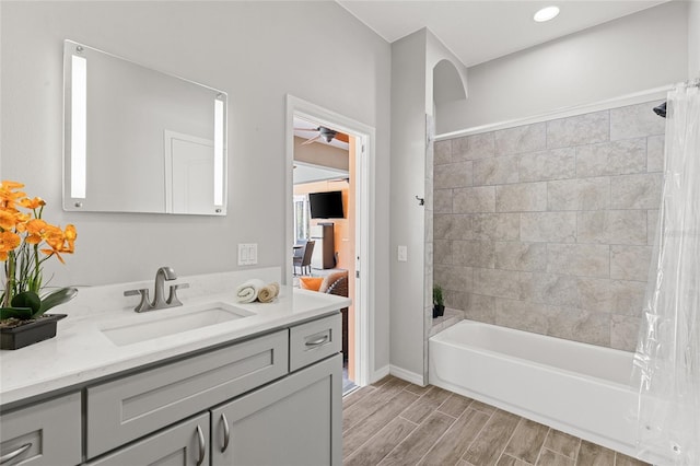 full bath featuring wood finished floors, vanity, baseboards, shower / bath combo, and ceiling fan