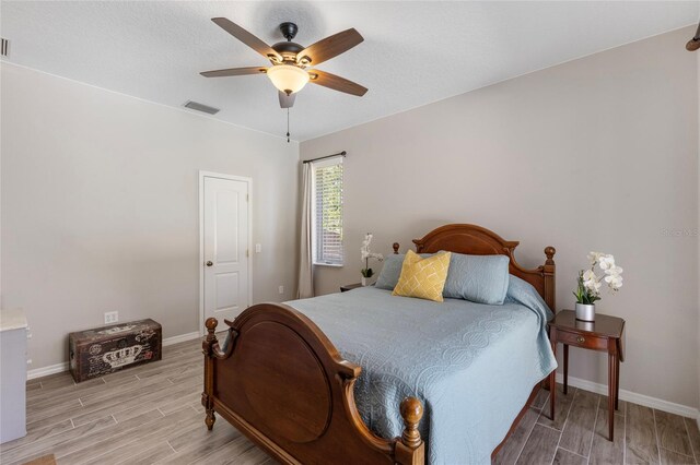bedroom featuring wood tiled floor, visible vents, baseboards, and ceiling fan