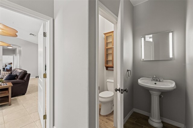 half bath featuring visible vents, toilet, and baseboards