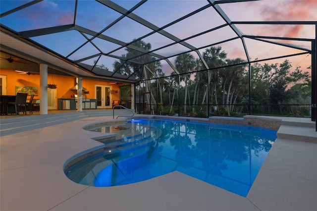 pool at dusk with a patio area, a ceiling fan, french doors, and an outdoor pool