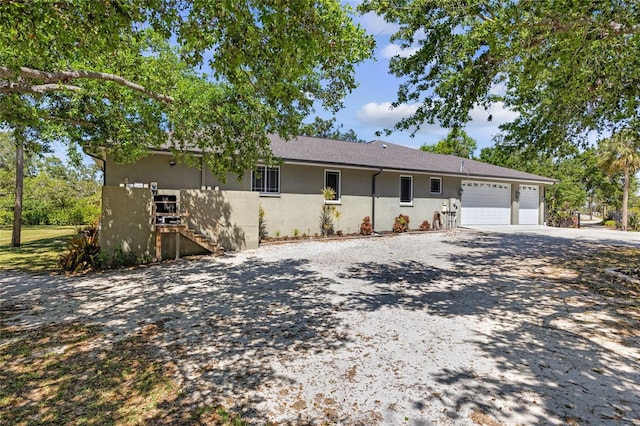 single story home featuring a garage, stucco siding, stairway, and concrete driveway