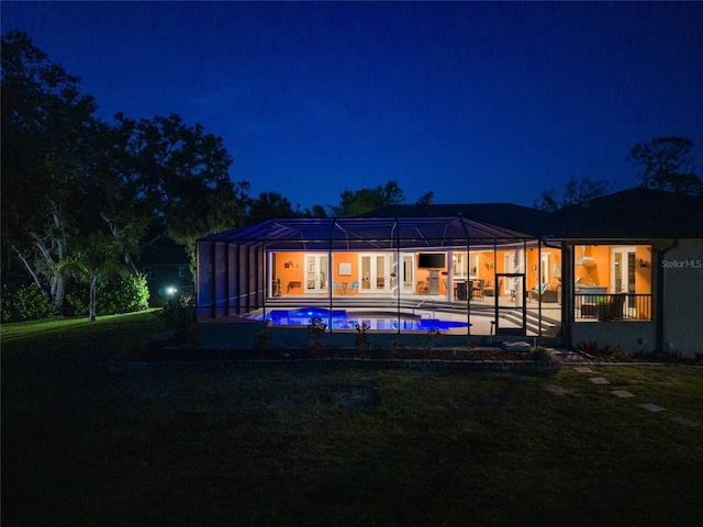 back of house at night featuring an outdoor pool, a patio area, and french doors
