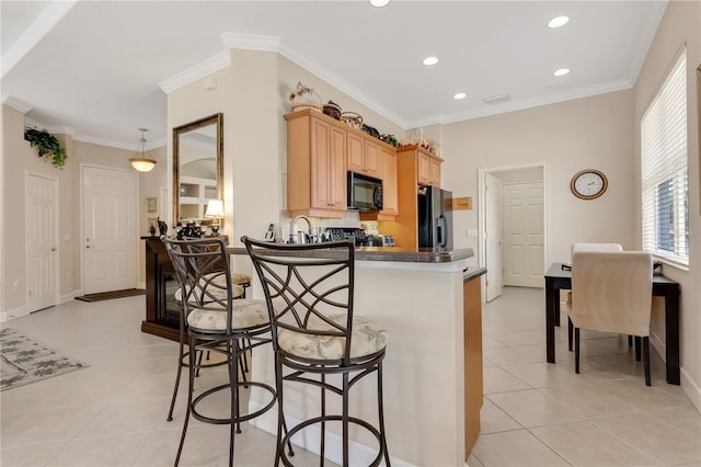 9818 Portside Ter, Bradenton, FL 34212 - kitchen with black appliances, a kitchen breakfast bar, light tile patterned floors, and light brown cabinets