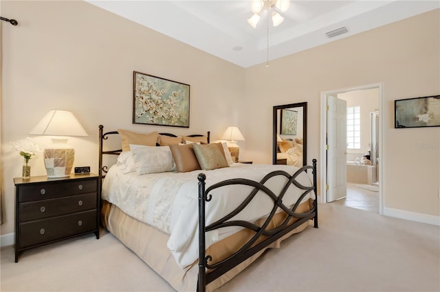 9818 Portside Ter, Bradenton, FL 34212 - bedroom with visible vents, baseboards, a raised ceiling, ensuite bath, and light colored carpet
