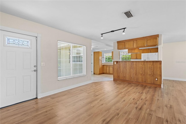 1665 Harmony Dr, Port Charlotte, FL 33952 - kitchen featuring freestanding refrigerator, light wood finished floors, brown cabinets, baseboards, and visible vents