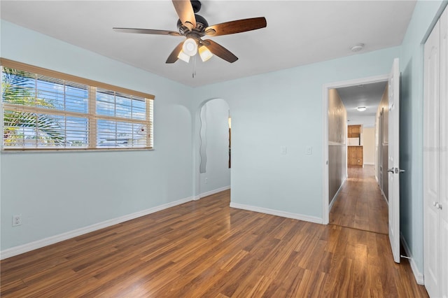 1665 Harmony Dr, Port Charlotte, FL 33952 - unfurnished bedroom with arched walkways, baseboards, ceiling fan, and wood finished floors