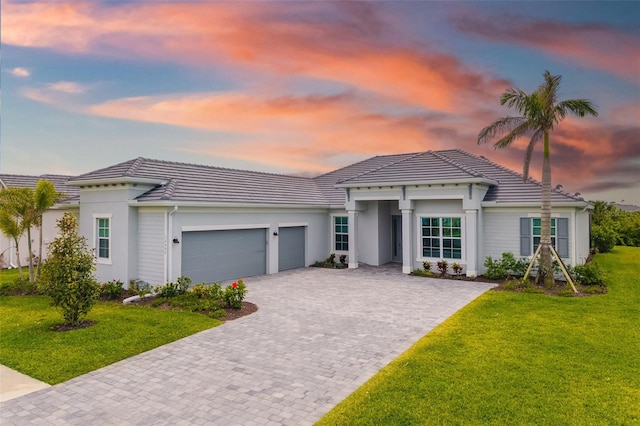 12557 Galapagos Ct, Venice, FL 34293 - view of front of home featuring a tile roof, decorative driveway, a garage, a front lawn, and stucco siding