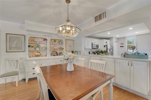 501 Lakeside Dr Unit 501, Bradenton, FL 34210 - dining area featuring a notable chandelier, crown molding, light wood-style floors, and visible vents