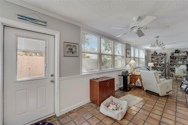 501 Lakeside Dr Unit 501, Bradenton, FL 34210 - living room featuring a wainscoted wall, a textured ceiling, a ceiling fan, and ornamental molding