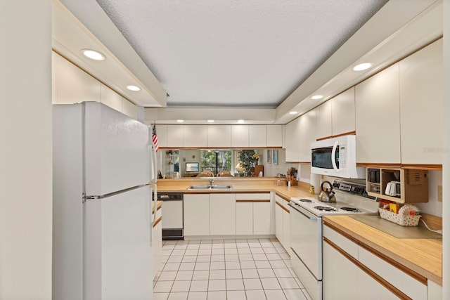 kitchen featuring recessed lighting, a sink, white appliances, and light countertops